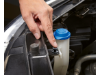 Hand pressing a Parkside® fastening clip on a car's windshield washer fluid reservoir.