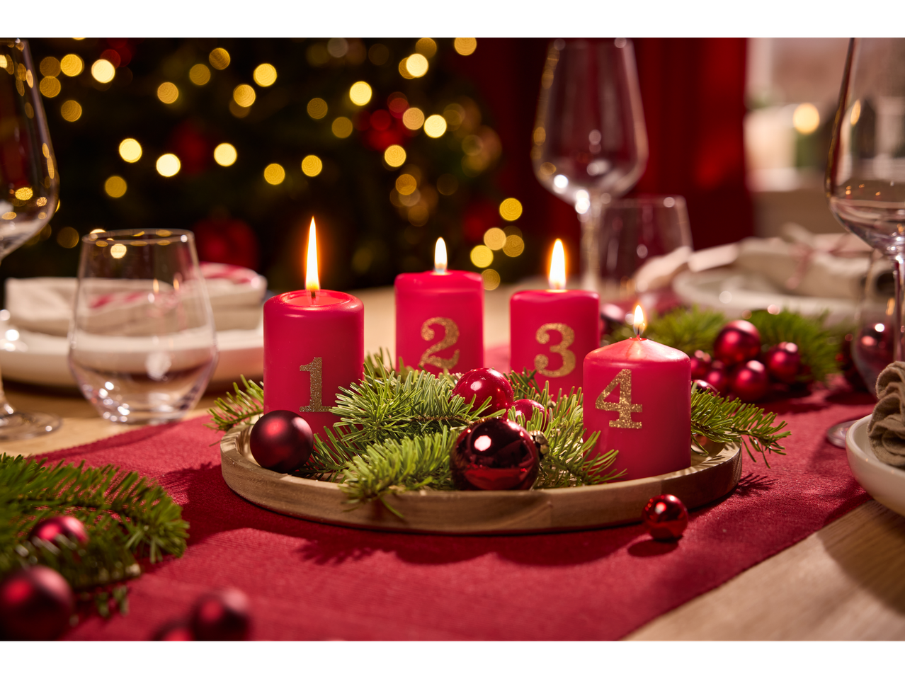 Set aus 4 roten Adventskerzen mit goldenen Zahlen auf einem festlichen Tisch