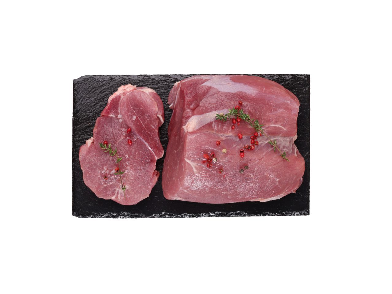 Dva komada sirovog svinjskog mesa sa začinima na crnoj ploči.