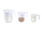 Three transparent measuring jugs of different sizes, filled with flour, brown sugar, and milk.