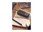 Black power bank charging on a notebook with a pen, laptop, and phone on a wooden desk.