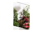 Garden bed with a solar-powered garden stake light, climbing plants, and pink flowers.
