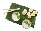Banana smoothies with mint and sliced bananas on a banana leaf with bamboo straws.