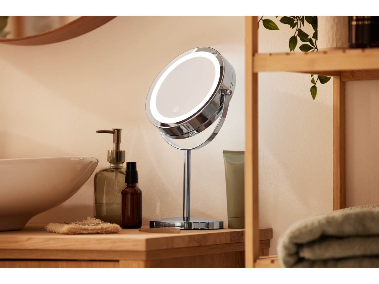 A lighted vanity mirror on a wooden bathroom counter with a sink and toiletries.