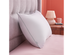 A Silentnight pillow sits on a blush pink bed, next to a grey headboard and a bedside table.
