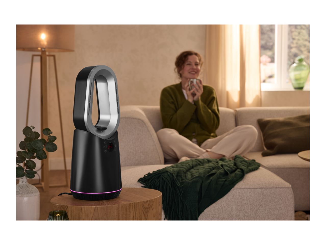 A modern black and silver bladeless heater fan on a wooden side table in a cozy living room.