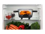 Open fridge with cooked chicken wings, ketchup, grapes, carrots, bell peppers, zucchini, and broccoli.