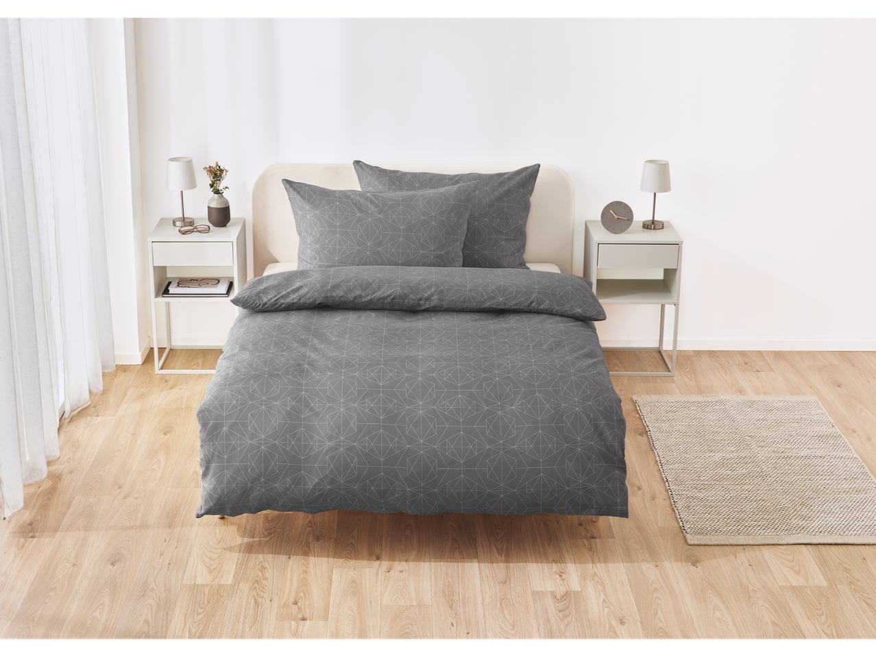 Gray duvet cover set with geometric pattern on a bed in a minimalist bedroom.