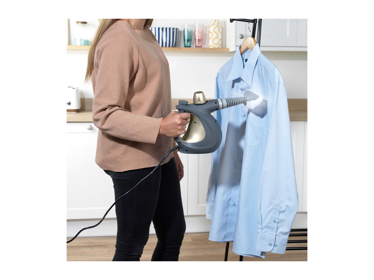 Woman steaming a light blue shirt with a handheld garment steamer.