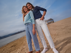 Δύο γυναίκες με casual μακρυμάνικες μπλούζες και τζιν σε αμμώδη παραλία.