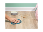 A person cleans up pet food crumbs on a floor using a cleaning mitt.