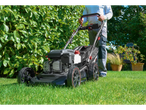 Man mowing lawn with a Parkside Performance® petrol lawnmower in a garden.