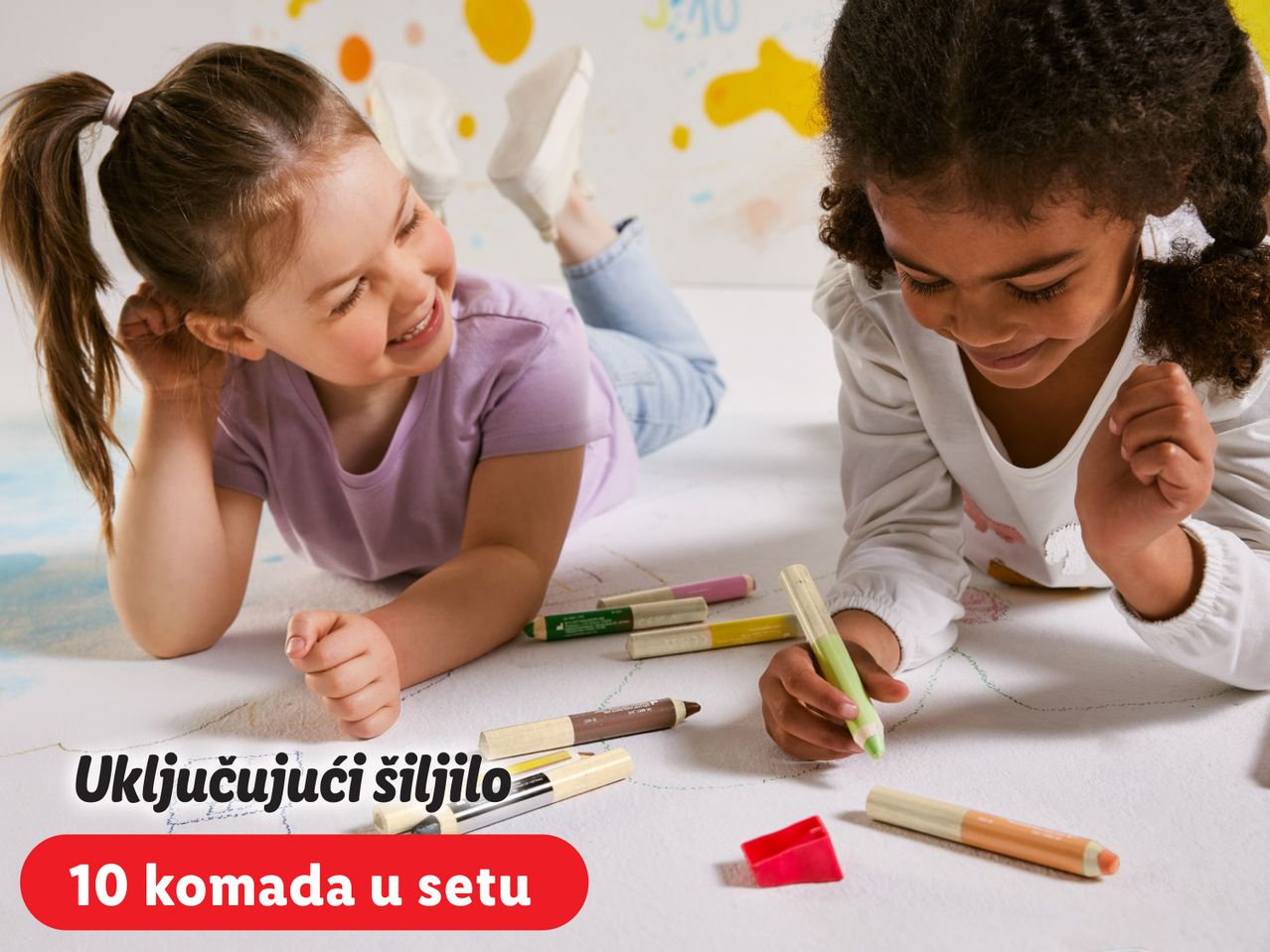 Dvije djevojčice crtaju na podu s flomasterima i bojicama.