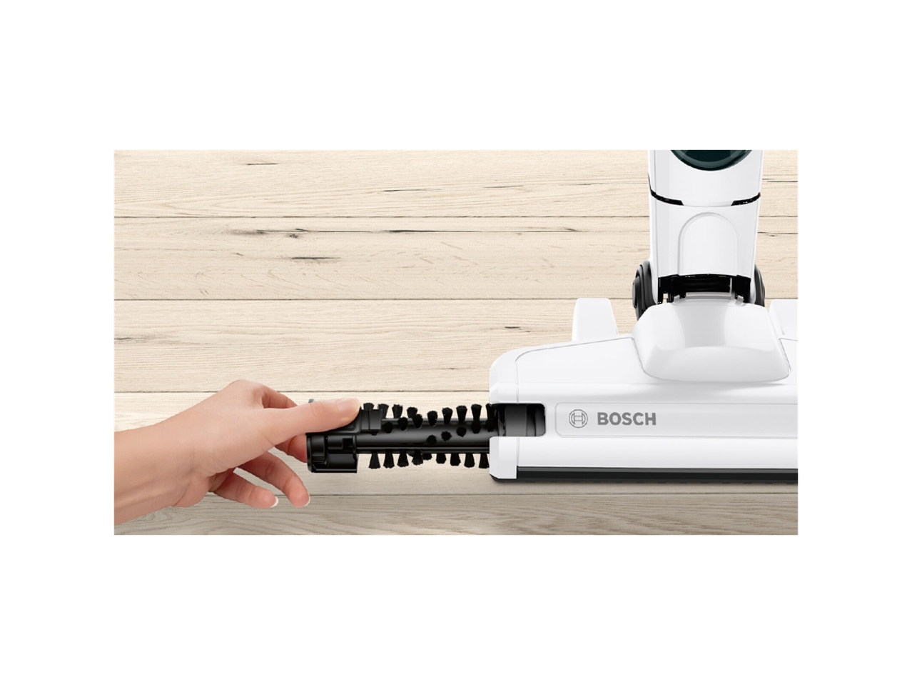 Hand removing brush from Bosch Cordless Vacuum Cleaner head on wooden floor.