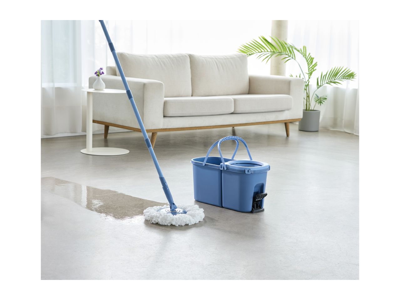 Blue spin mop and bucket cleaning a light-colored floor in a living room.