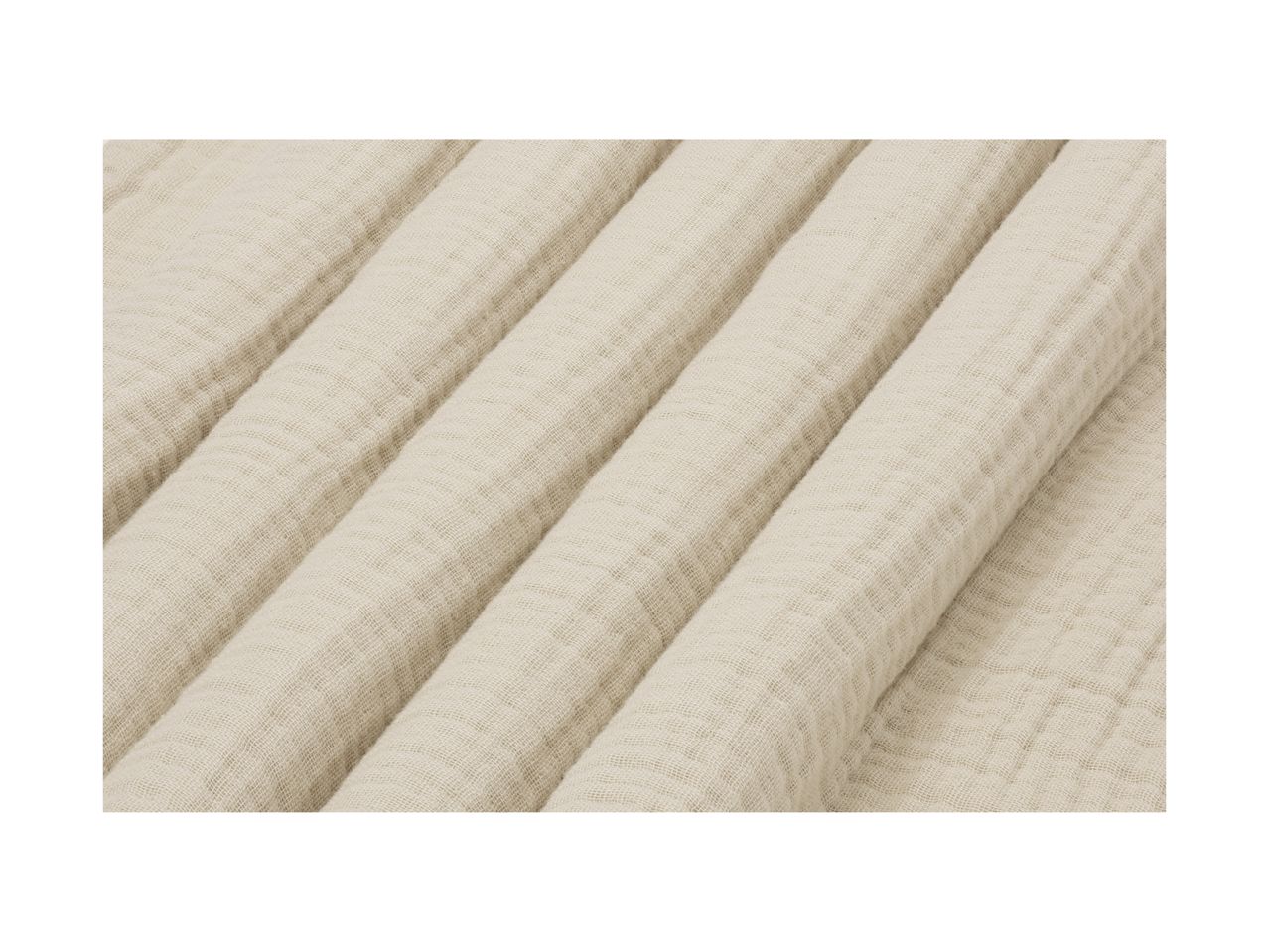 Close-up of a beige, textured muslin fabric, folded in soft, diagonal pleats.