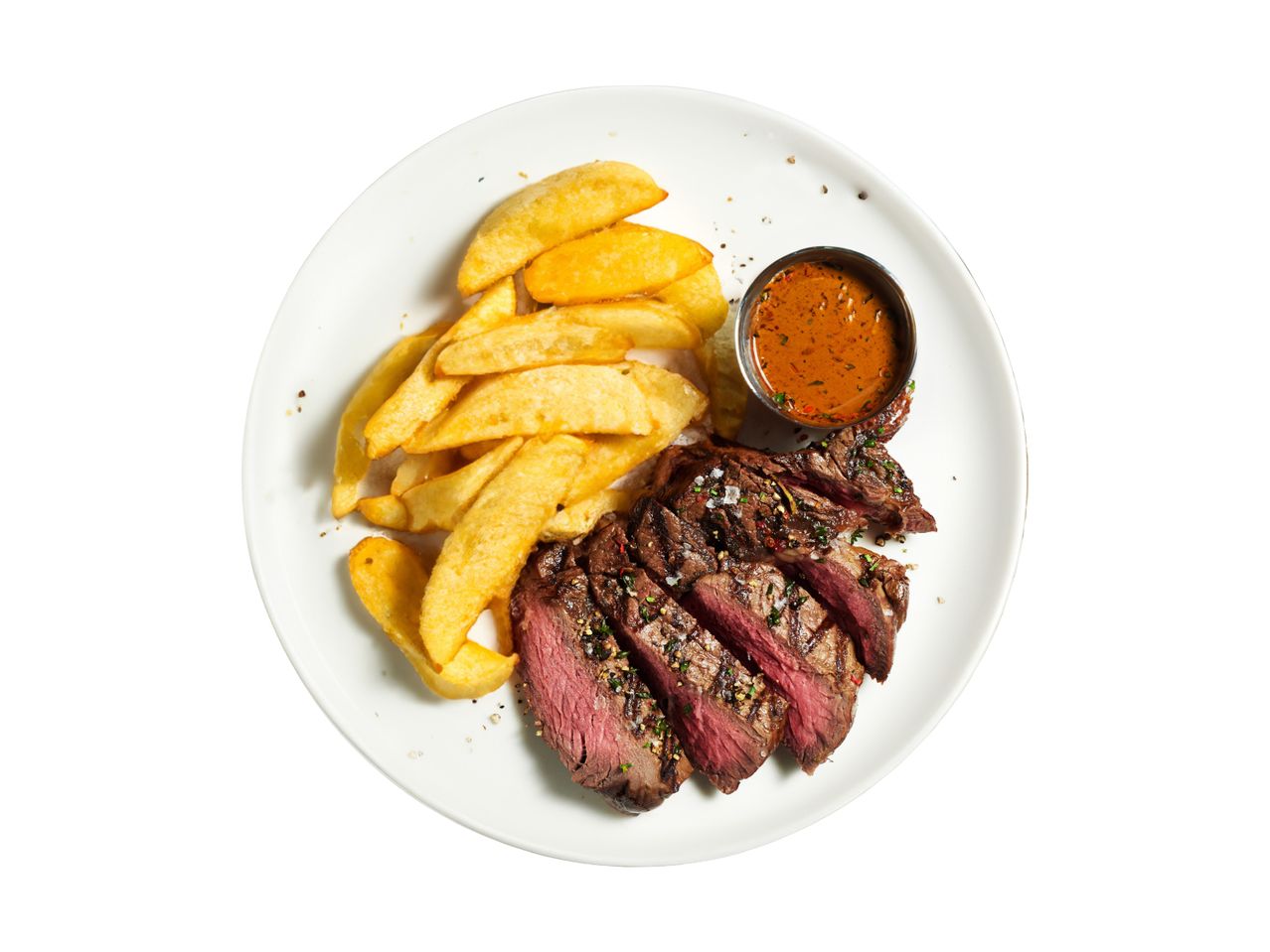 Sliced steak with potato wedges and a small bowl of sauce.