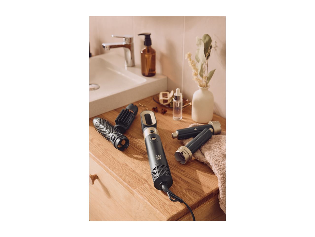 Hair styler with interchangeable brush and curling attachments on a bathroom counter.