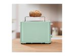 Mint green toaster with a bread roll on a warming rack on a wooden counter.