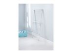 White clothes drying rack leaning against a light blue wall, with a laundry basket