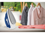 Fier de călcat cu aburi Tefal® pe o masă de călcat, cu haine în fundal.