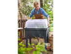 Frau im Garten öffnet Parkside® Hochbeet mit transparenter Haube.