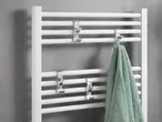 White towel warmer with chrome hooks and a green towel.