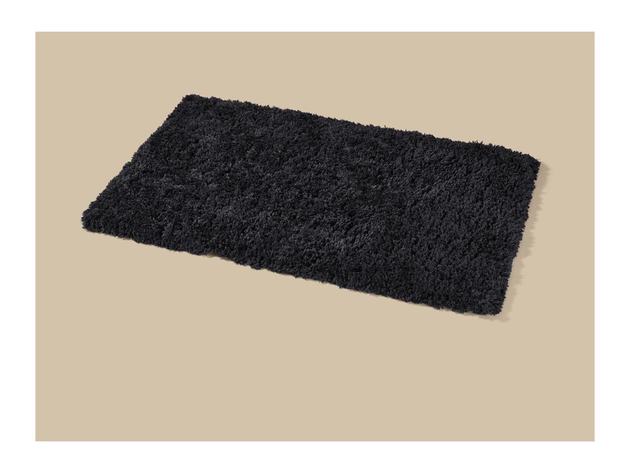 A rectangular black shag rug or bath mat on a light beige background.