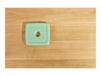 Light green square ice pack with a circular hole in the center, on a wooden surface.