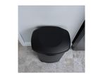 Top-down view of a black trash can with a lid on a patterned floor.