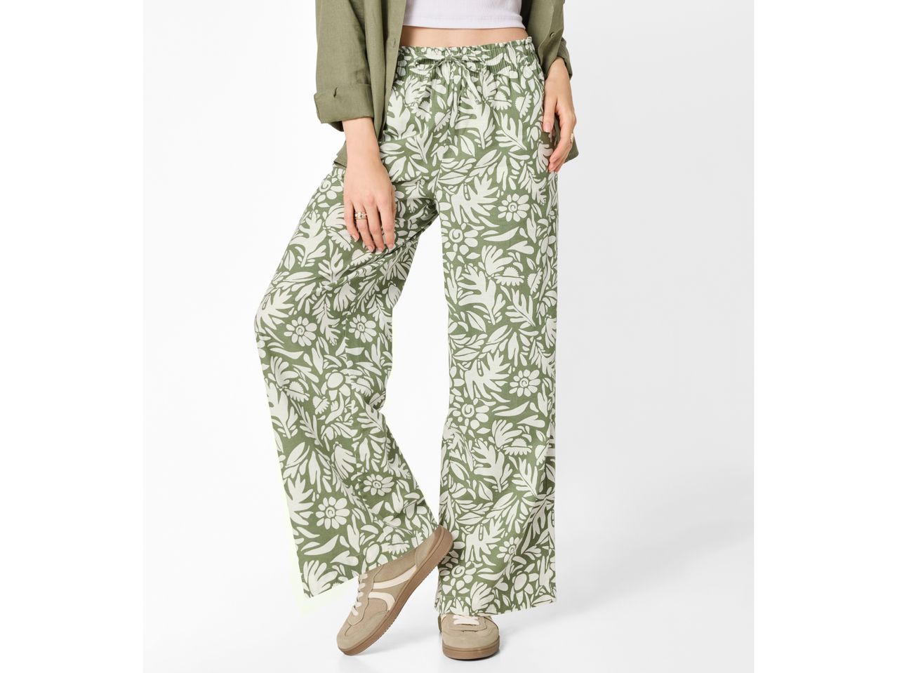 Woman wearing green floral wide-leg trousers, a white crop top, and a green jacket.