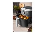 An air fryer filled with roasted potatoes on a kitchen counter.