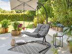 Outdoor patio with a grey hanging chair, umbrella, potted plants, and a small side table.