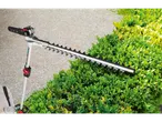 Long-handled hedge trimmer next to a bush.