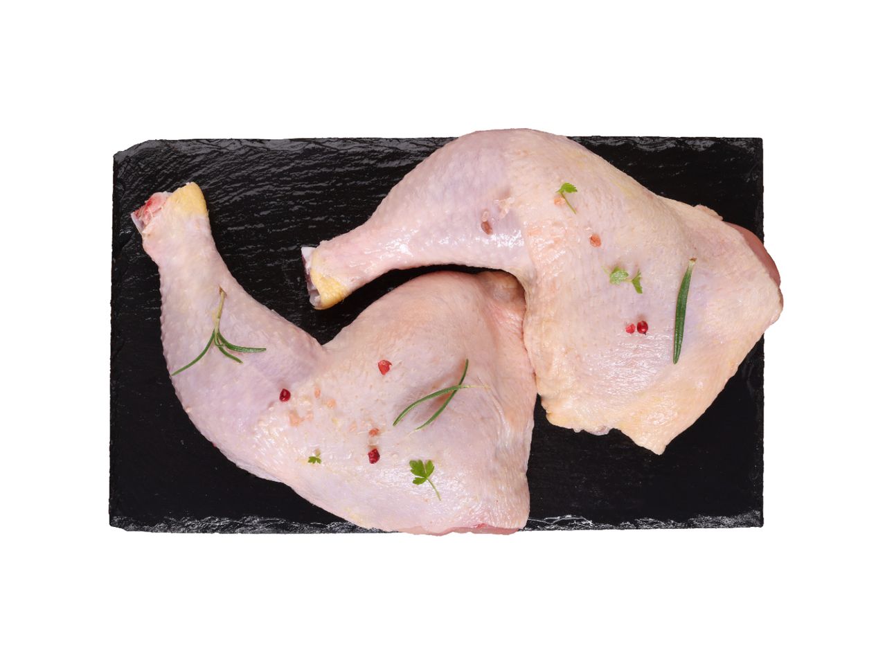 Dva sirova pileća bataka sa začinima na crnoj ploči.