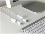 Cabluri USB și FireWire în organizatoare albe de cabluri, cu o tastatură și un monitor Apple.