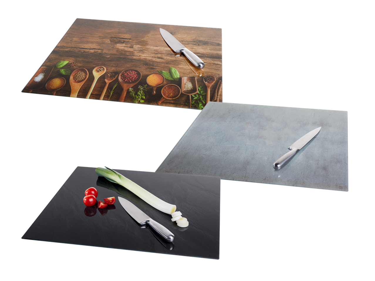 Tri steklene deske za rezanje z noži, začimbami, porom in paradižnikom.