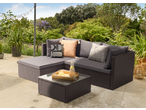 Outdoor rattan corner sofa with grey cushions and a glass-top coffee table on a patio.