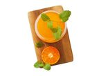 Orange juice with mint leaves and a sliced orange on a wooden board.