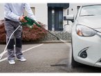 A person washes their car with a pressure washer.