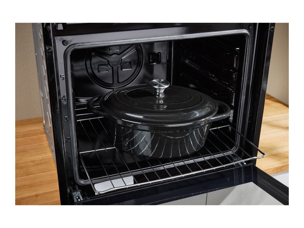 Black cast iron pot inside an open oven on a metal rack