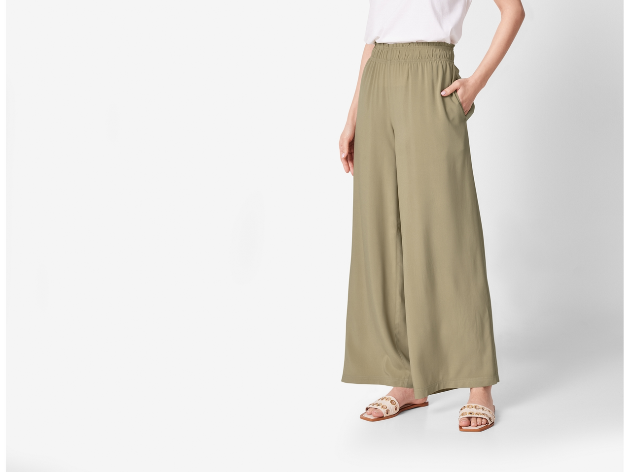 Pantaloni largi de culoare verde măsliniu cu sandale plate.