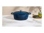 Blue cast iron pot with lid, olive oil, and rosemary on a marble surface.