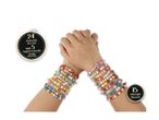 Hands wearing colorful beaded bracelets with words and charms, including 24 bracelets and 15 charms.