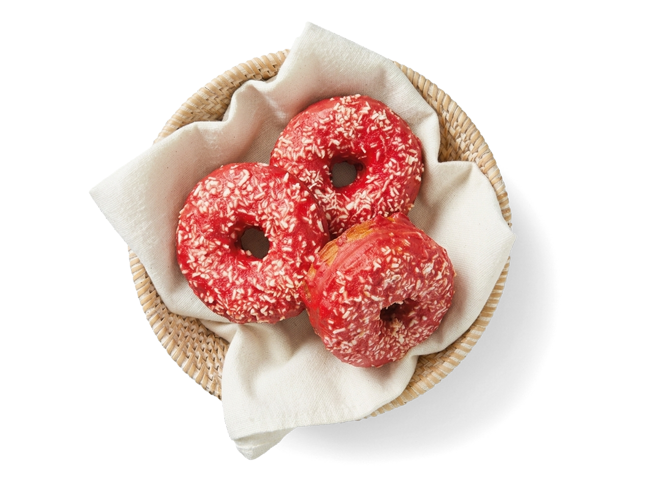 Drie rode donuts met kokosvlokken in een rieten mand met een witte doek.