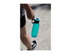 A person holding a turquoise water bottle while walking on a gravel path.