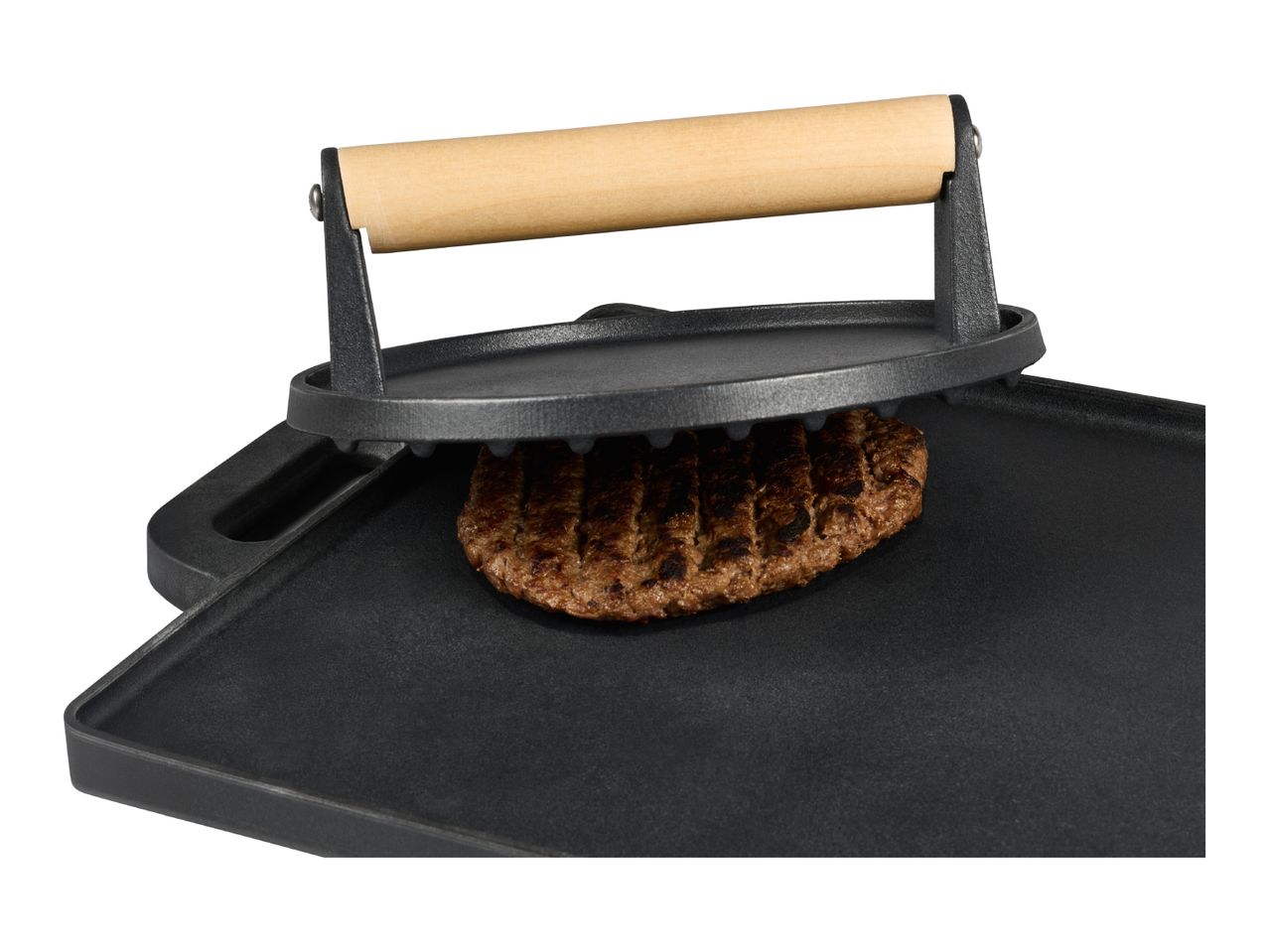 Cast iron grill press with a wooden handle on a griddle, pressing a burger patty.