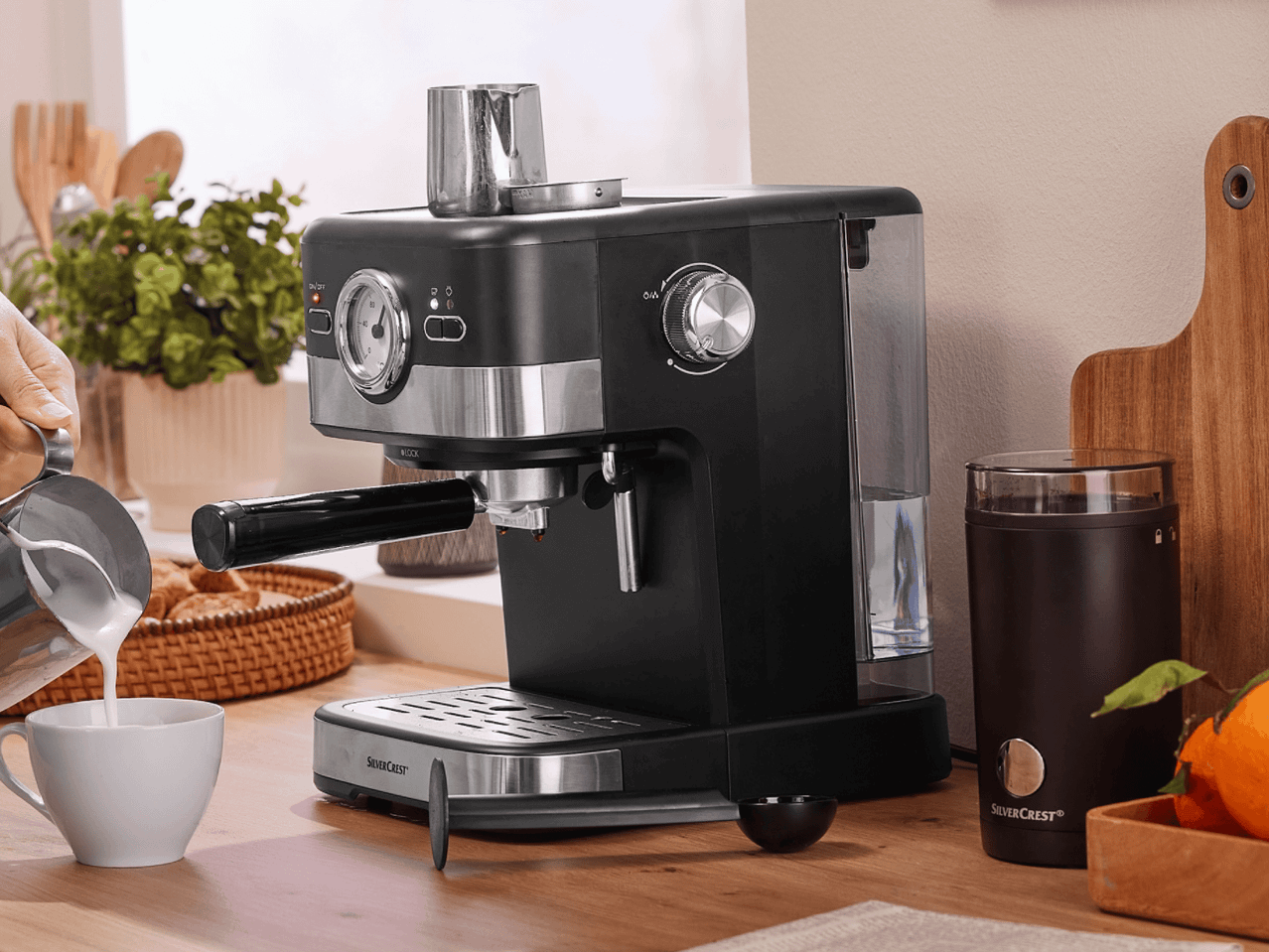 SilverCrest Espressomaschine und Kaffeemühle auf einer Küchenarbeitsplatte mit Milch und Orangen