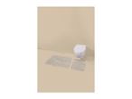 Two beige striped bath mats on a light brown floor with a white toilet.