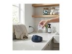 Person pouring water into a garment steamer on a countertop next to a laundry basket.